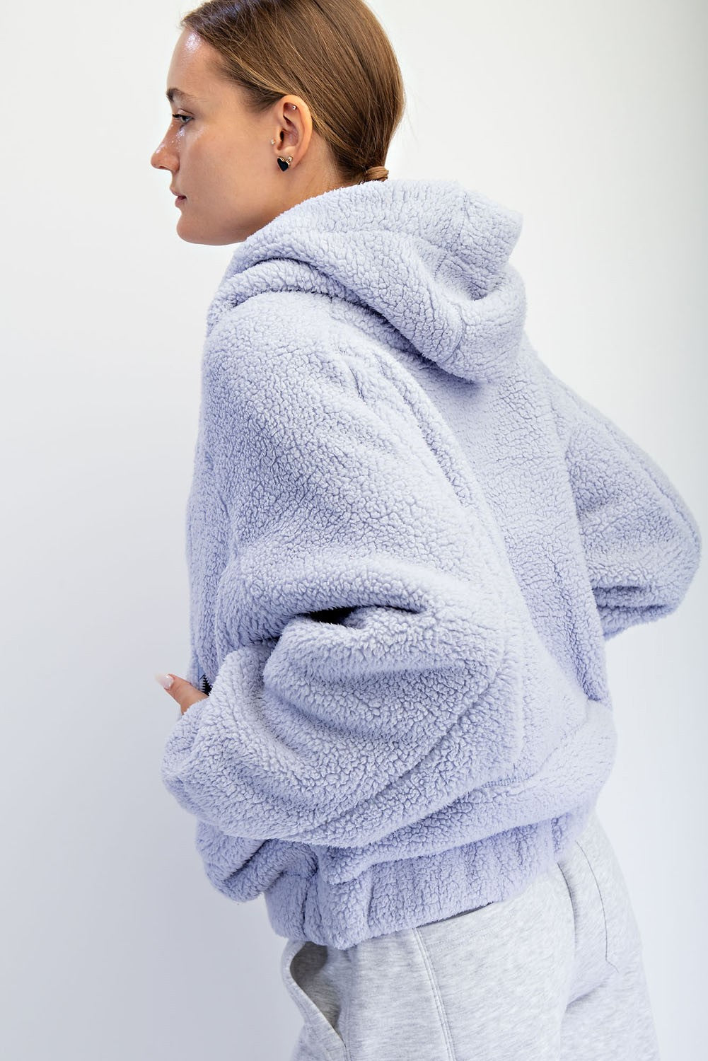 woman wearing a lavender plush hoodie with a relaxed fit and hood, styled with gray sweatpants