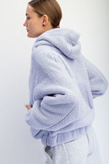 woman wearing a lavender plush hoodie with a relaxed fit and hood, styled with gray sweatpants
