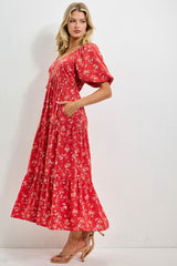 woman wearing a red floral midi dress with puff sleeves and pockets, standing sideways against a white background