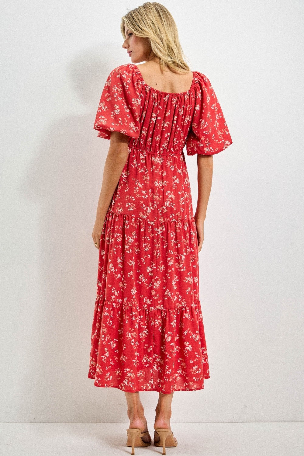 woman wearing a red floral maxi dress with puff sleeves and a tiered skirt, viewed from the back