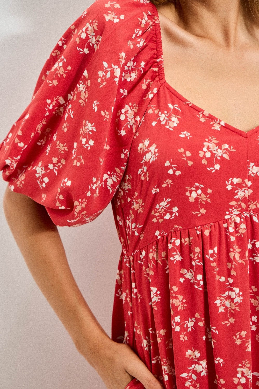 woman wearing a red floral print dress with puff sleeves and a v-neckline