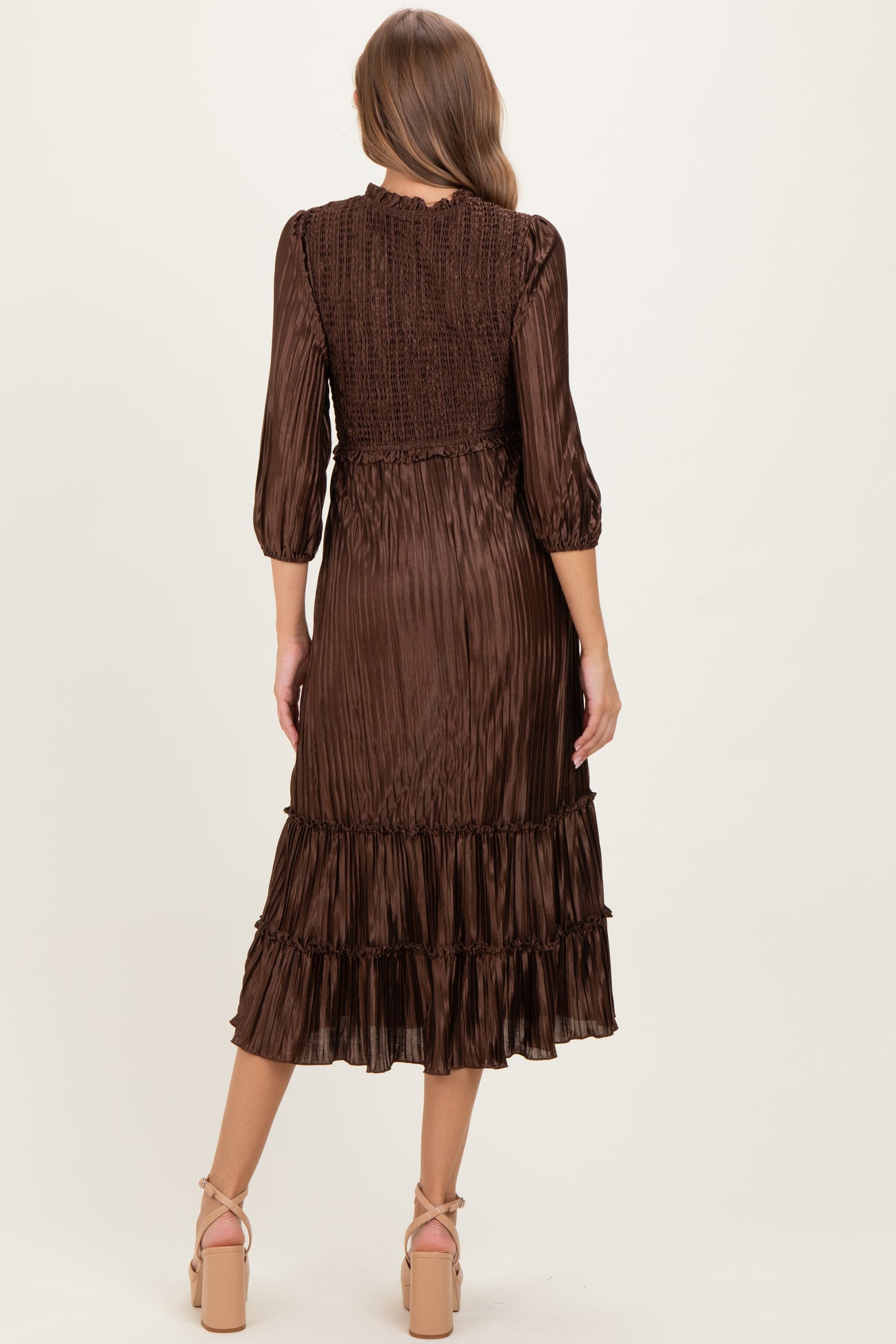 woman wearing a brown maternity dress with three-quarter sleeves and a tiered ruffle hem, showcasing a smocked back