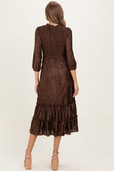 woman wearing a brown maternity dress with three-quarter sleeves and a tiered ruffle hem, showcasing a smocked back