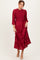 woman wearing a burgundy long sleeve pleated dress with ruffle details and a smocked bodice