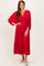 woman wearing a red pleated midi dress with long sleeves and a deep v-neckline