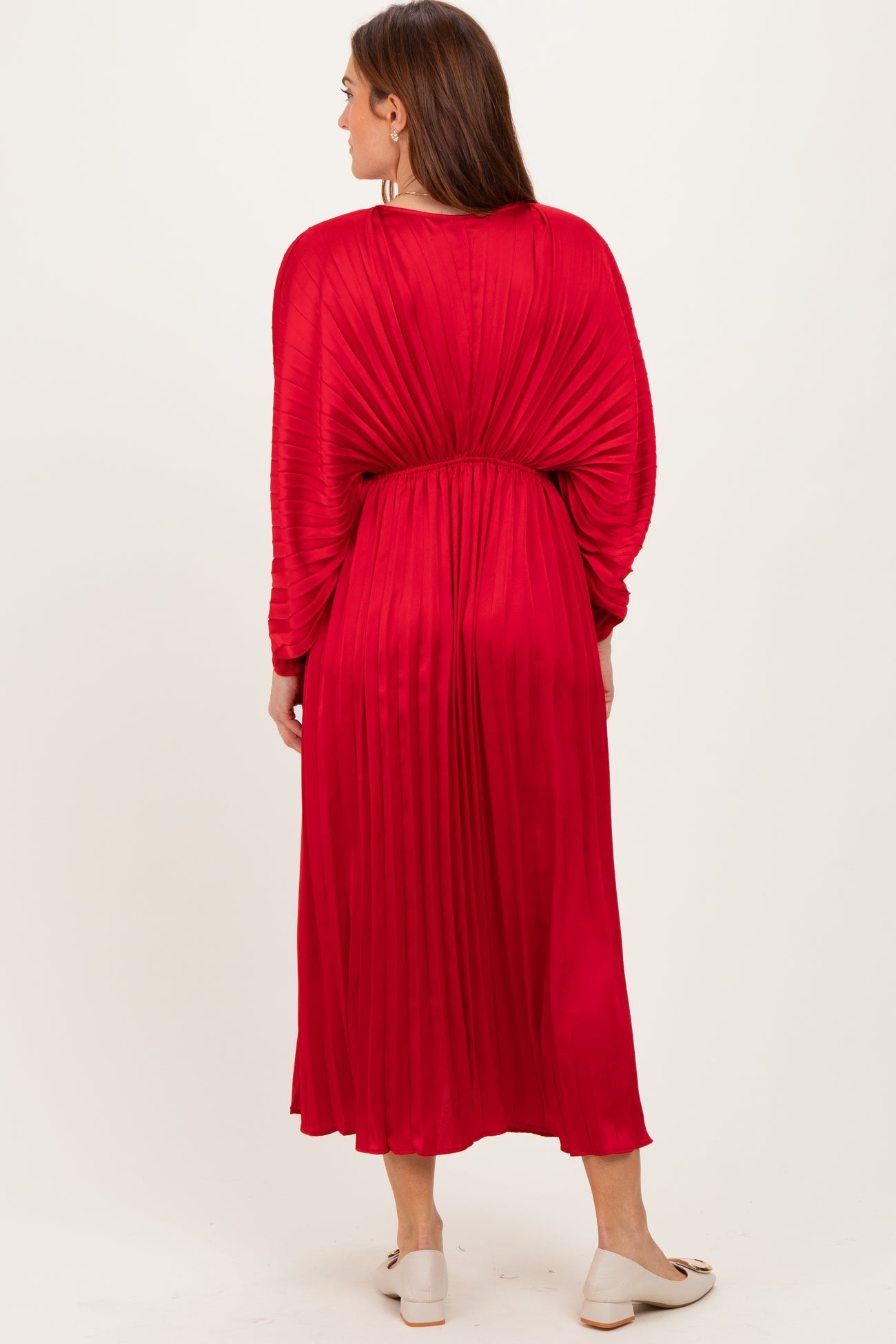 woman wearing a red pleated long sleeve dress, showing the back view and a flowy silhouette