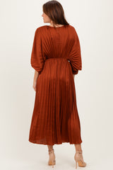 woman wearing a rust-colored pleated midi dress with a cinched waist and balloon sleeves, showing the back view