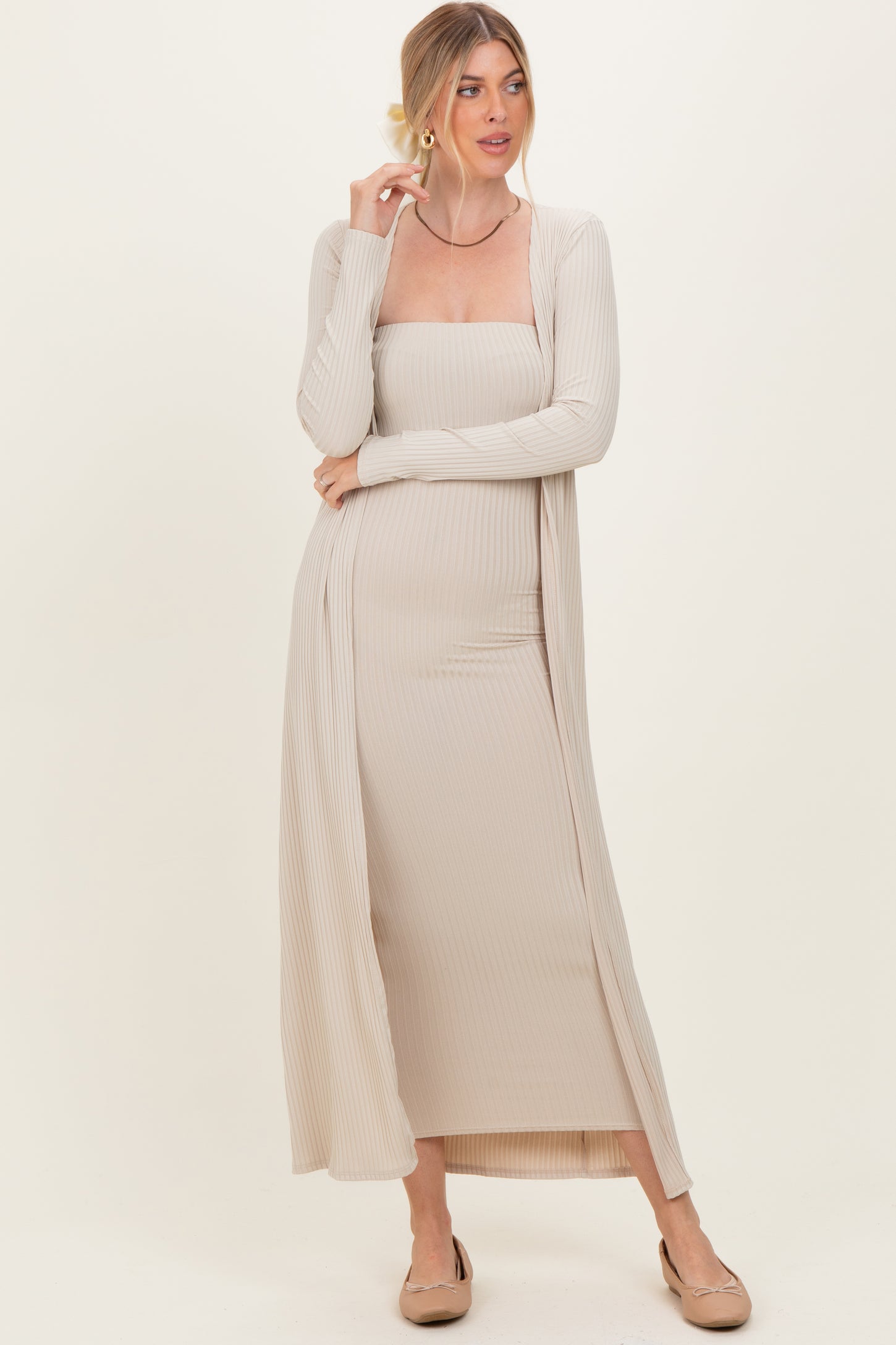 woman wearing a beige ribbed maxi dress with a matching cardigan and beige flats, standing with arms crossed