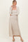 woman wearing a beige ribbed maxi dress with a matching cardigan and beige flats, standing with arms crossed