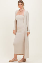 woman wearing a beige ribbed strapless dress with a matching long cardigan and flat shoes