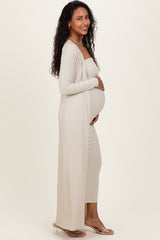 woman wearing a beige ribbed maternity maxi dress with long sleeves and holding her baby bump