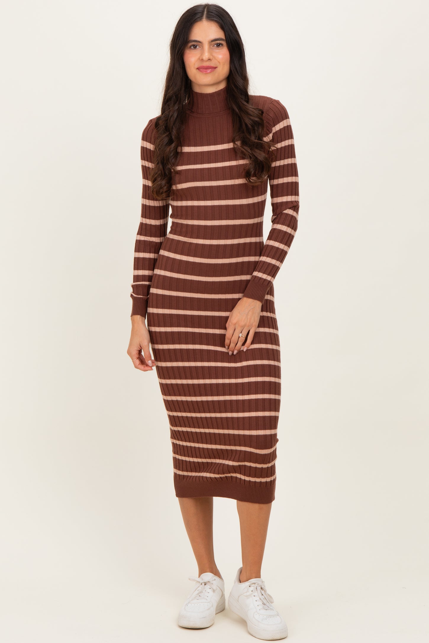 woman wearing a brown and beige striped ribbed midi dress with long sleeves and a high neckline, paired with white sneakers