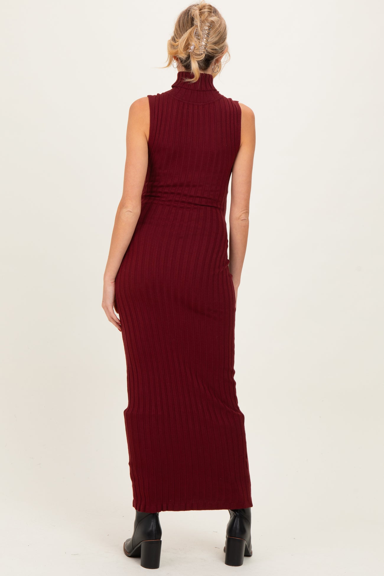 woman wearing a burgundy ribbed maternity maxi dress with a high neck, shown from the back