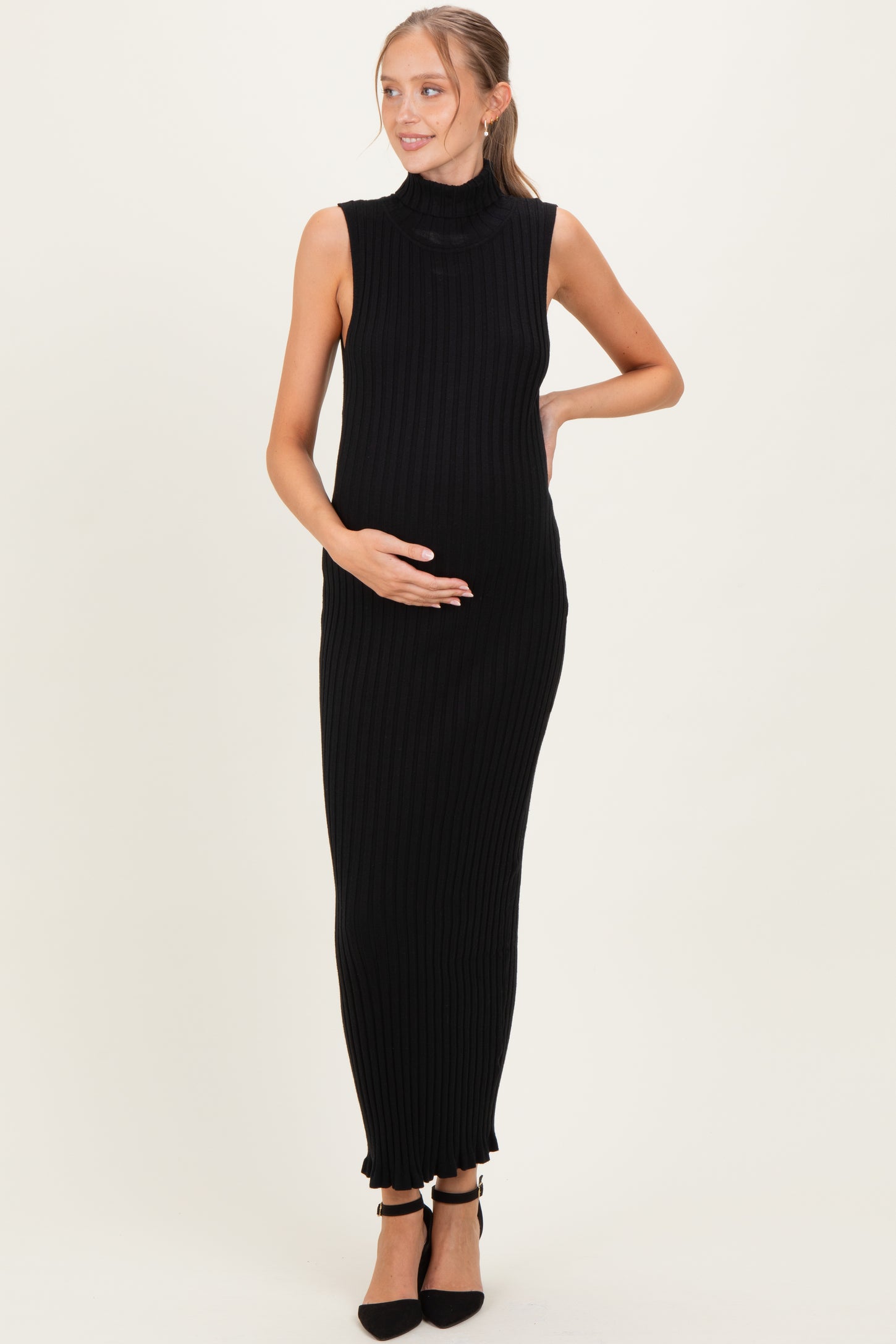 woman wearing a black ribbed sleeveless maternity dress and holding her baby bump