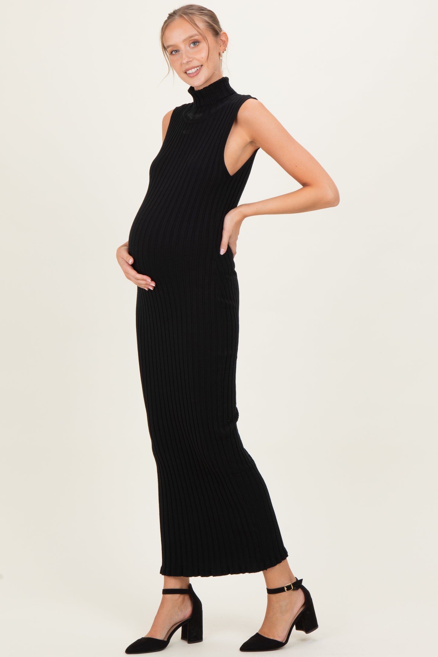woman wearing a black ribbed sleeveless maternity dress, highlighting her baby bump with a smile