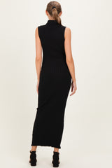woman wearing a fitted black ribbed maternity dress with a sleeveless design and a long silhouette, side slit visible