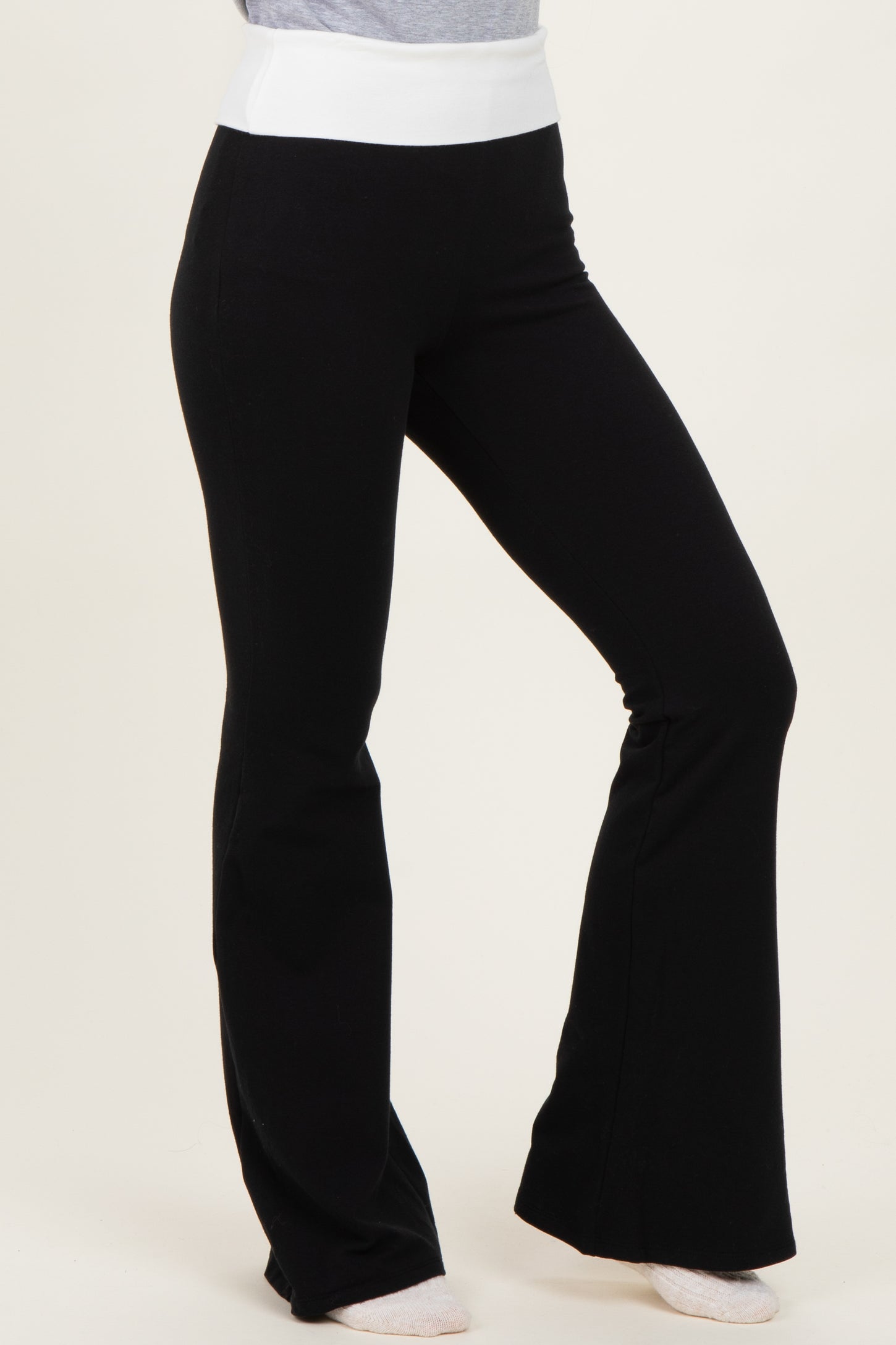 woman wearing black flared pants with a white waistband, styled with a casual top