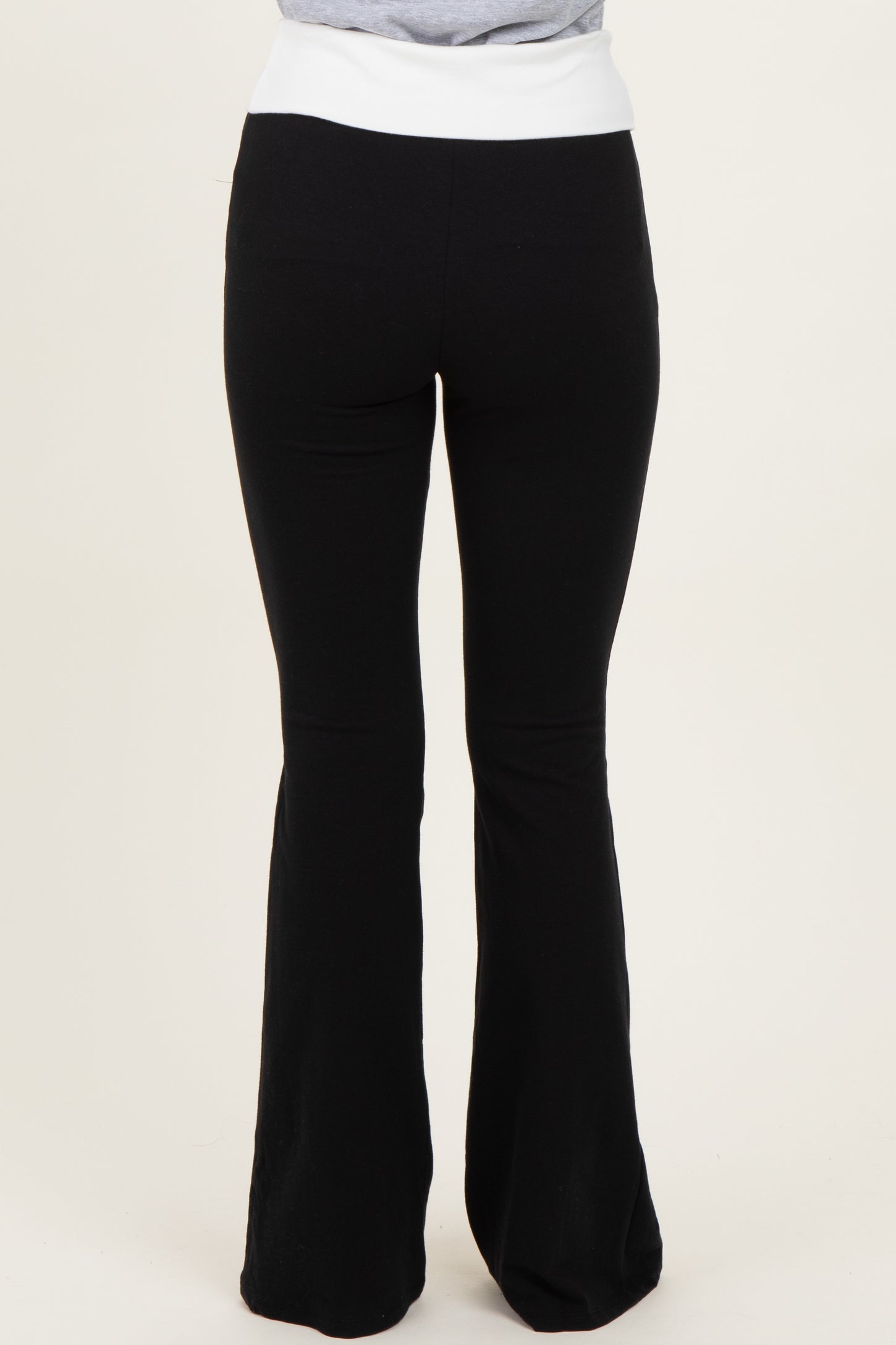 woman wearing black flared yoga pants with a white waistband, seen from the back