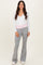 woman wearing a white long sleeve wrap top and grey flared sweatpants with a pink waistband