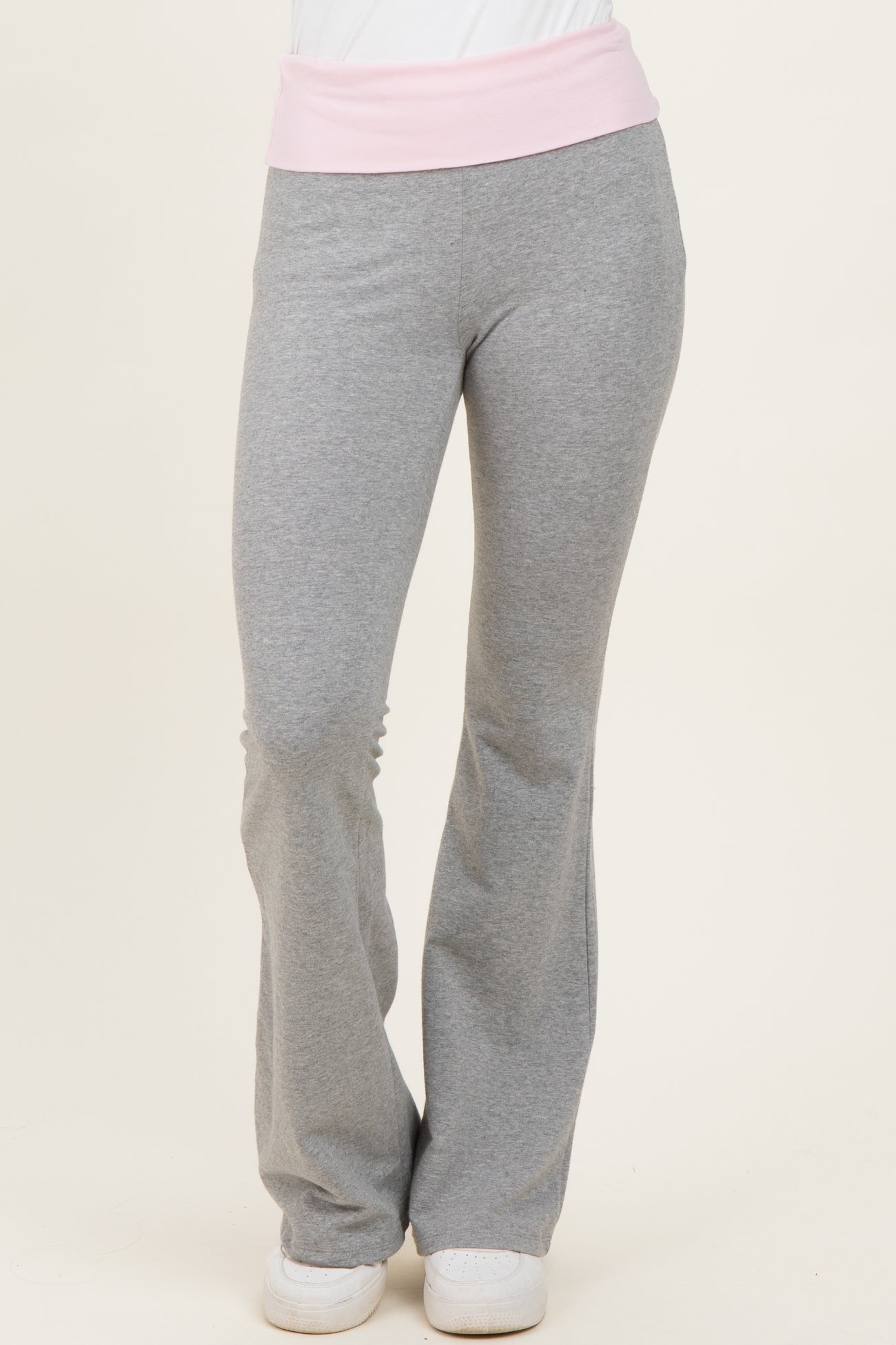 woman wearing gray flared sweatpants with a light pink waistband and white sneakers