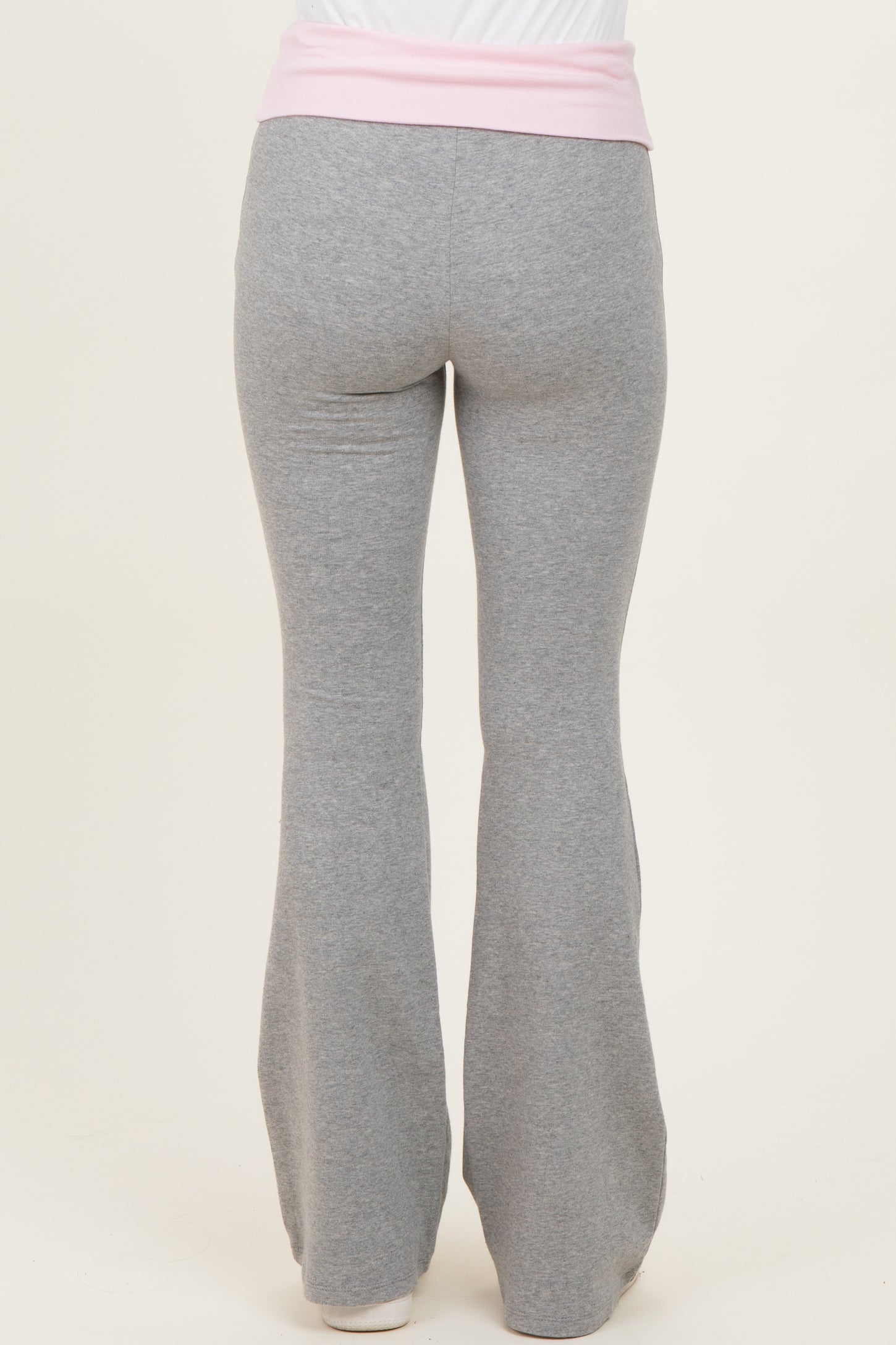 woman wearing gray flared yoga pants with a pink waistband, viewed from the back