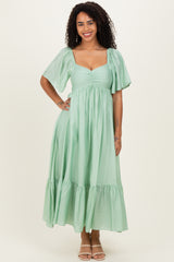 woman wearing a mint green maxi dress with puff sleeves and a tiered hemline