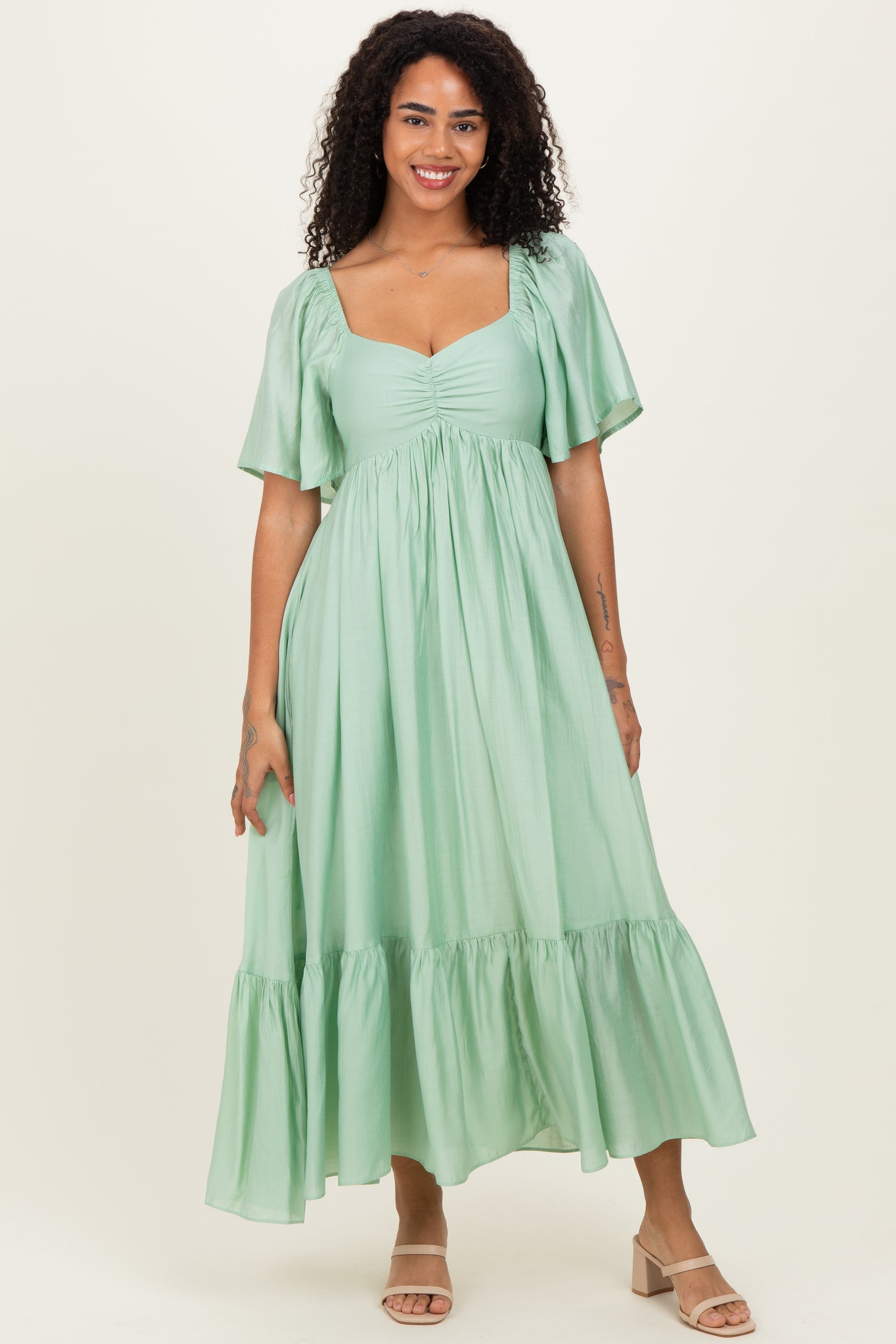 woman wearing a mint green short sleeve maxi dress with a ruched bust and tiered ruffle hem