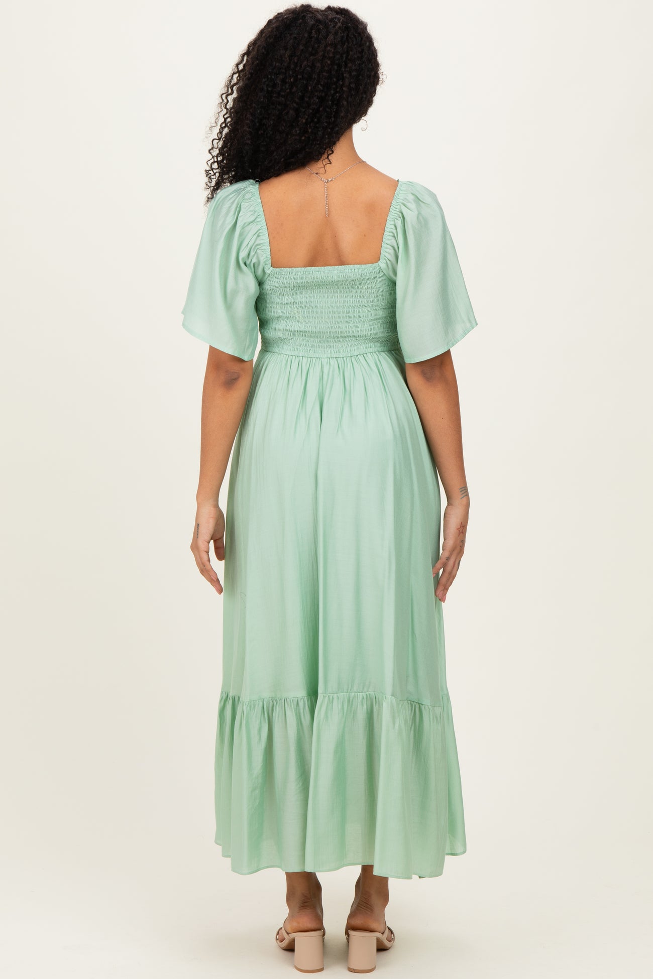 woman wearing a mint green smocked back maxi dress with short puff sleeves and a tiered hem