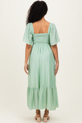 woman wearing a mint green smocked back maxi dress with short puff sleeves and a tiered hem