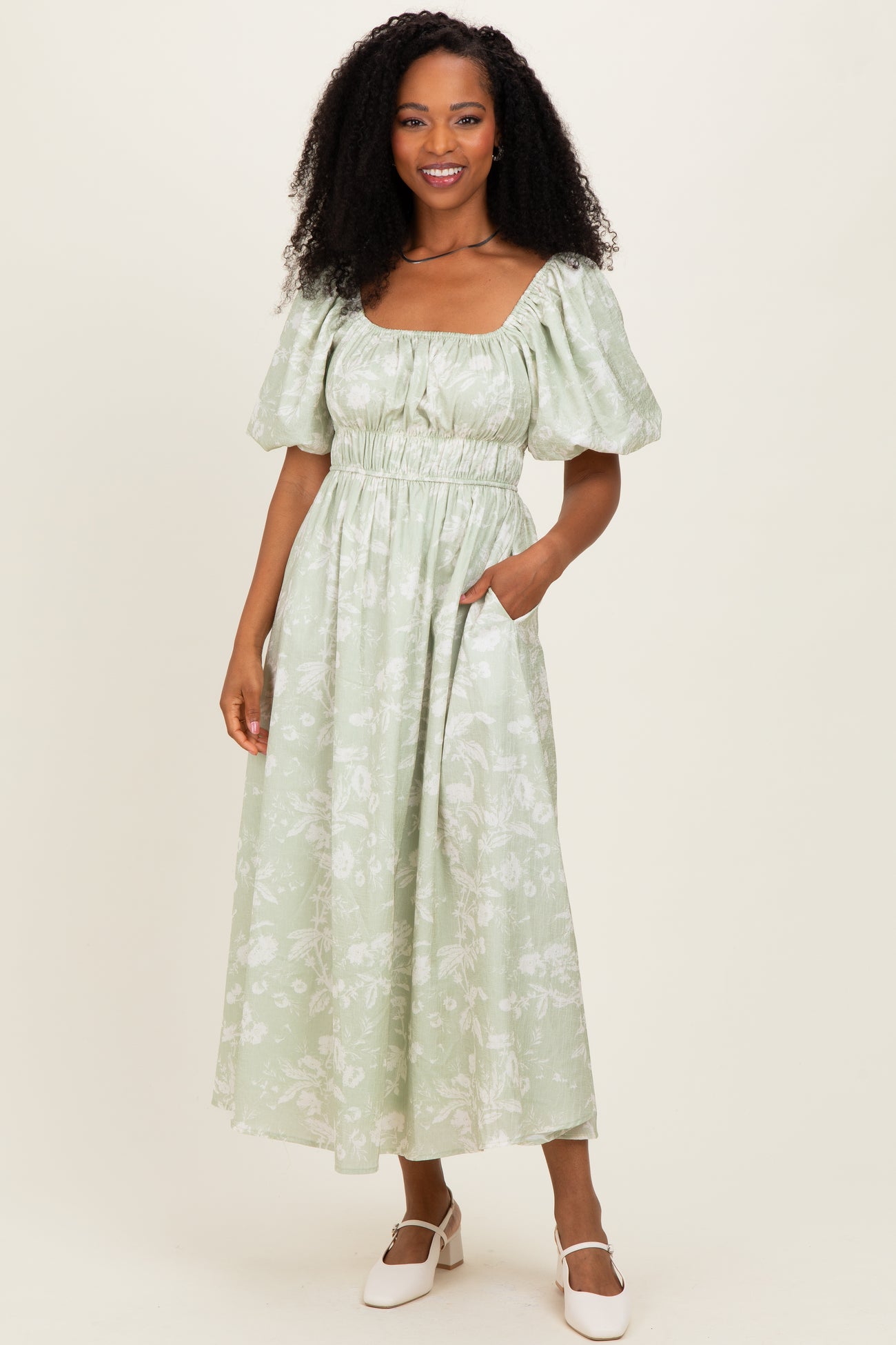 woman wearing a light green floral maxi dress with puff sleeves and a square neckline