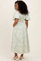 woman wearing a light green midi dress with puff sleeves and a cinched waist, standing with her back to the camera