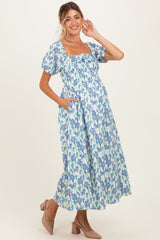 woman wearing a floral print maternity dress with puff sleeves and pockets, showcasing her baby bump.