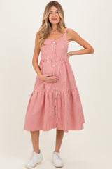 woman wearing a red and white striped maternity dress with buttons, holding her baby bump