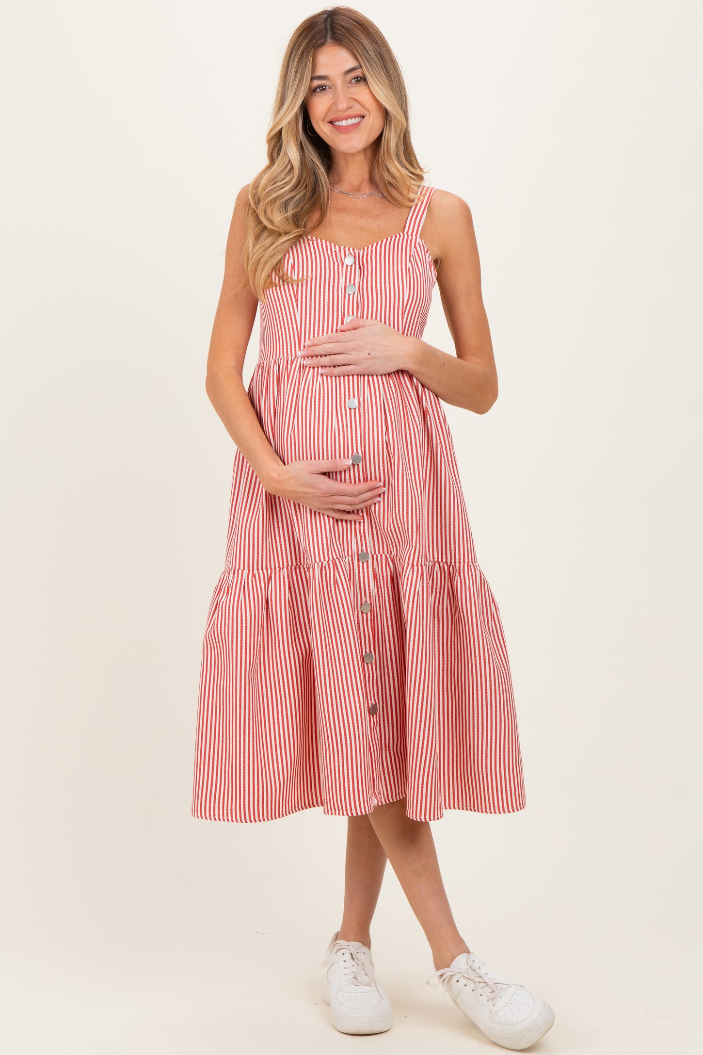 woman wearing a red and white striped maternity dress with buttons and a tiered skirt, holding her baby bump