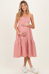 woman wearing a red and white striped maternity dress with buttons and a tiered skirt, holding her baby bump