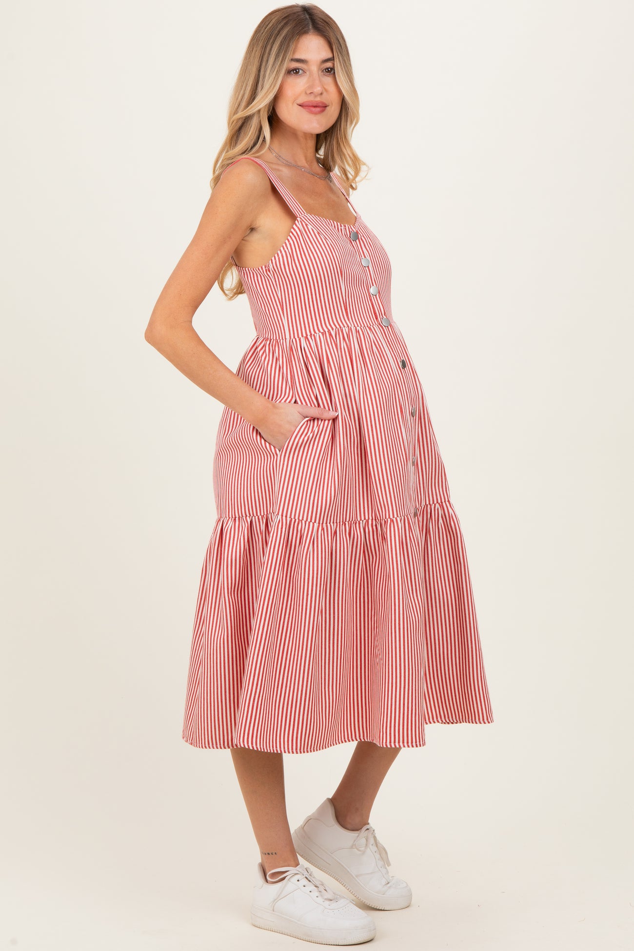 woman wearing a red and white striped maternity dress with buttons and pockets, showcasing her baby bump