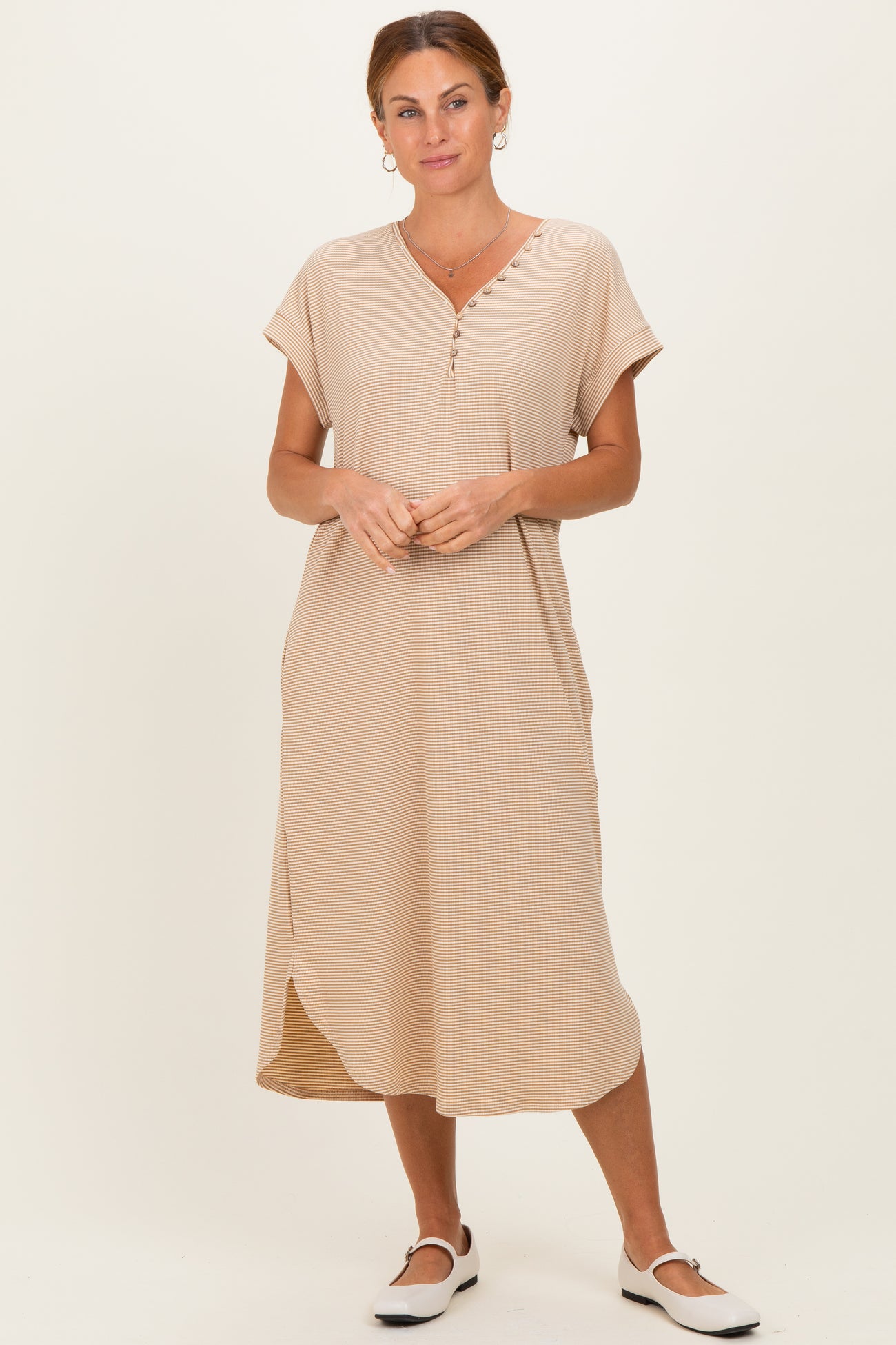 woman wearing a beige short sleeve midi dress with button details and side slits, standing against a neutral background