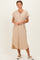 woman wearing a beige short sleeve midi dress with button details and side slits, standing against a neutral background