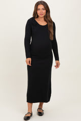 woman wearing a black long sleeve maternity dress with a scoop neckline and side tie detail, showcasing her baby bump
