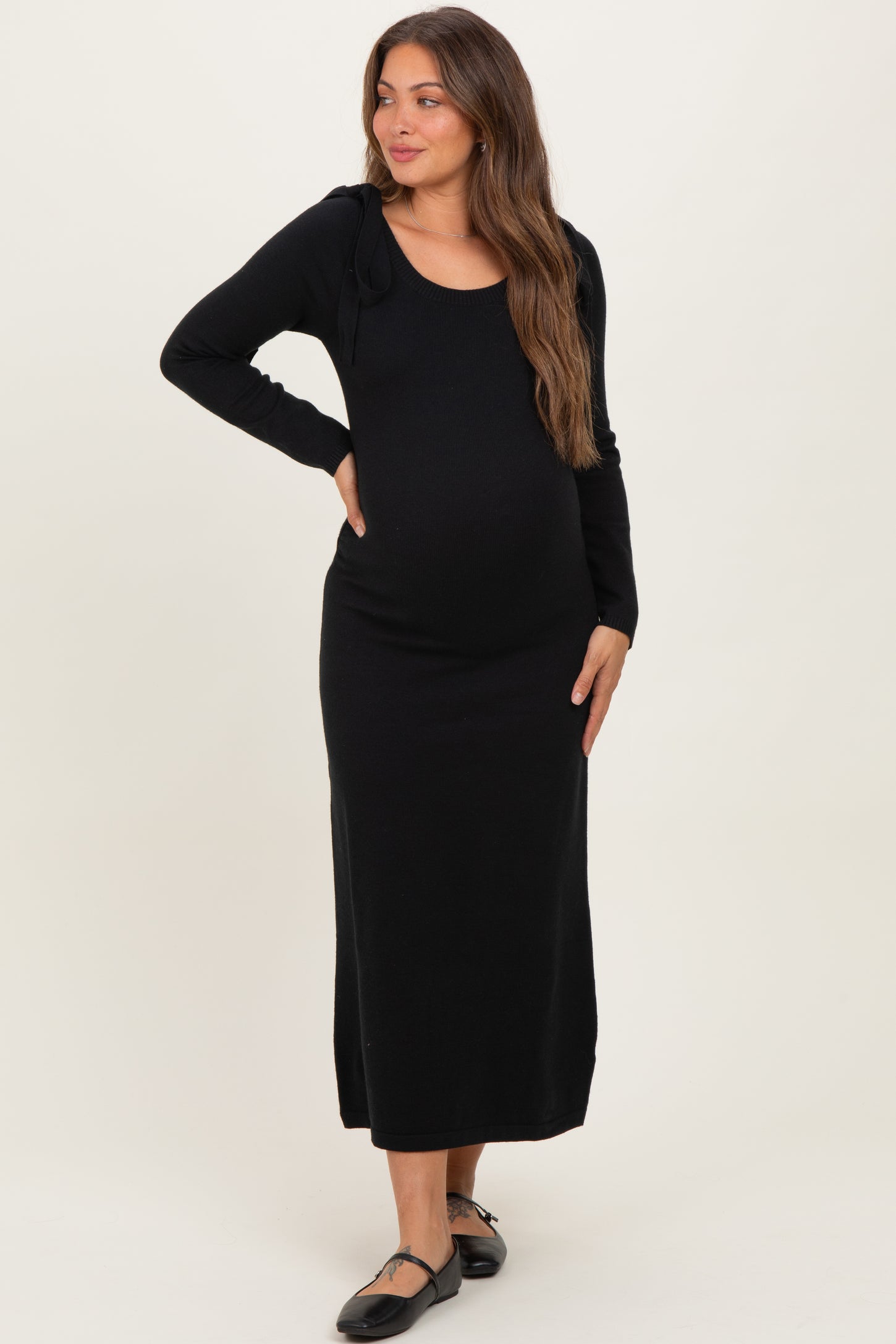 woman wearing a black long sleeve maternity dress with tie details and visible baby bump