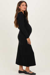woman wearing a black long sleeve maternity dress with a bow detail and showing her baby bump
