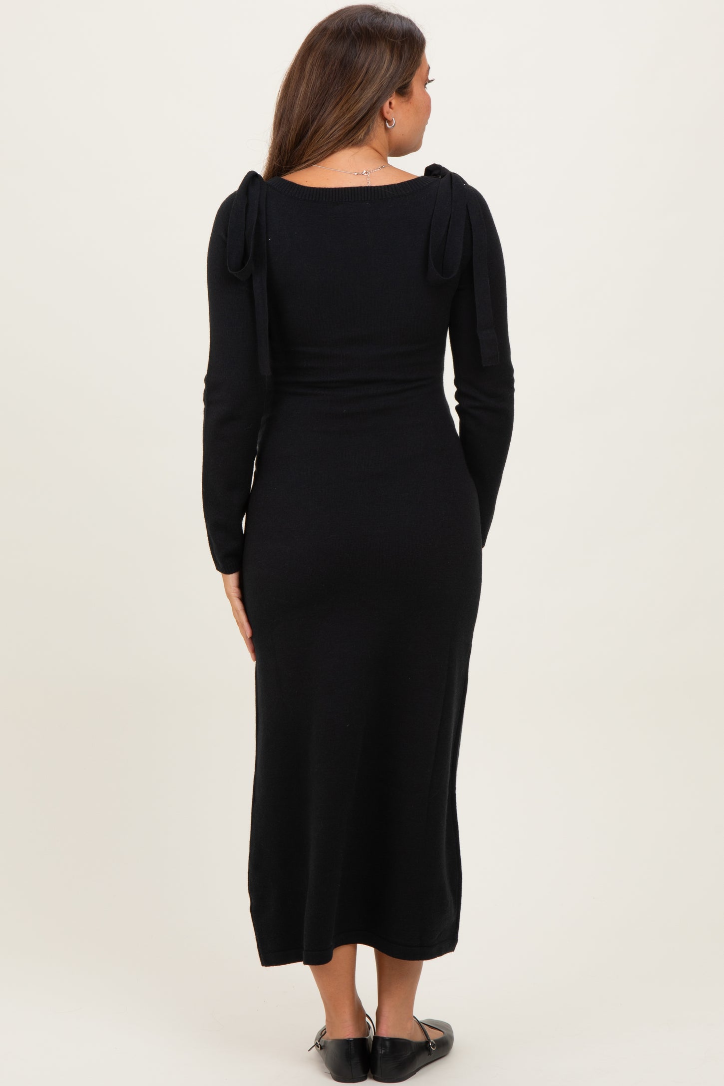 woman wearing a black long sleeve maternity dress with tie details on the shoulders