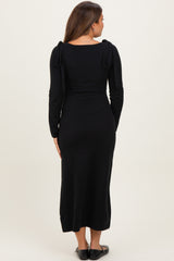 woman wearing a black long sleeve maternity dress with tie details on the shoulders