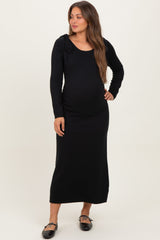 woman wearing a black long sleeve maternity dress with a fitted silhouette and shoulder tie details, showing a baby bump