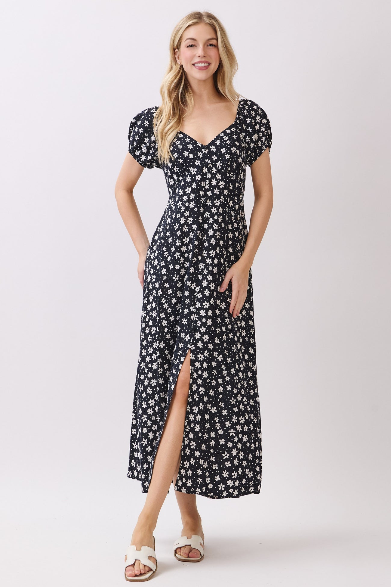 woman wearing a navy blue floral maxi dress with puff sleeves and a thigh-high slit