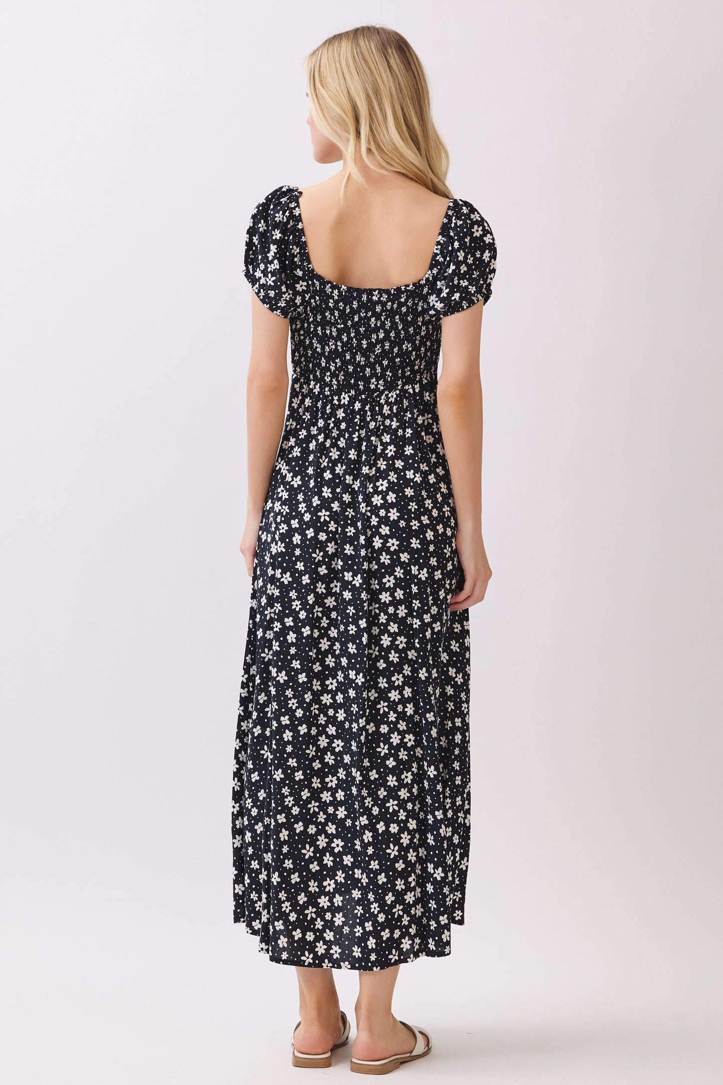 woman wearing a black floral maxi dress with short puff sleeves and a fitted bodice, showing the back view