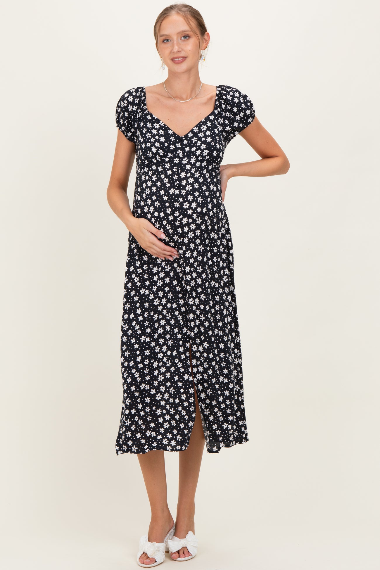 woman wearing a black floral midi maternity dress and holding her baby bump