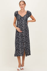 woman wearing a black floral midi maternity dress and holding her baby bump