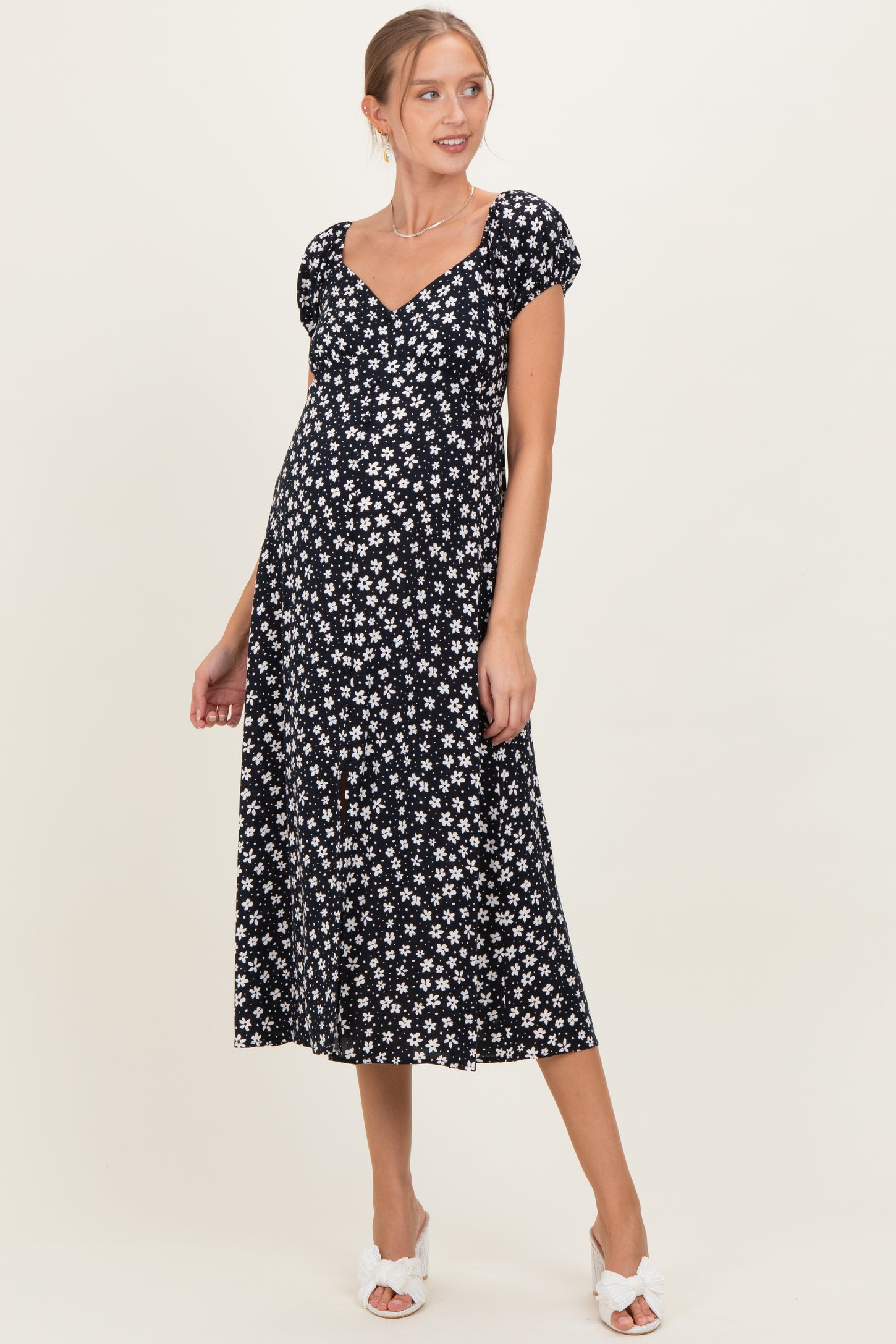 woman wearing a black floral maternity dress with puff sleeves and v-neckline, showcasing her baby bump