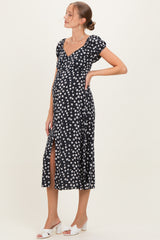woman wearing a navy blue maternity dress with white floral print and a side slit, showing her baby bump
